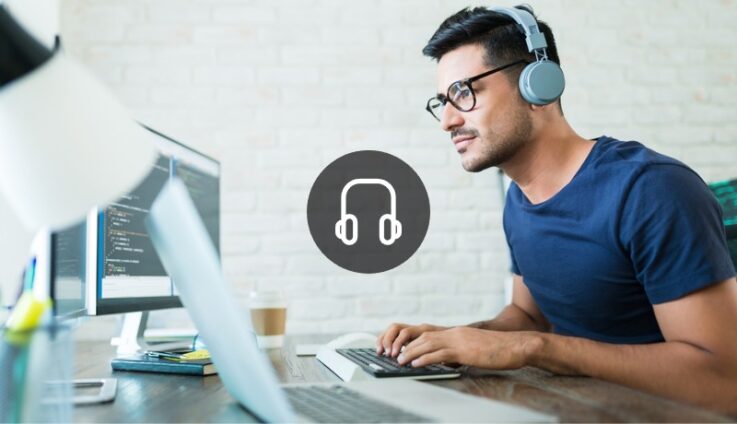 Man with headphones typing looking at computer screen