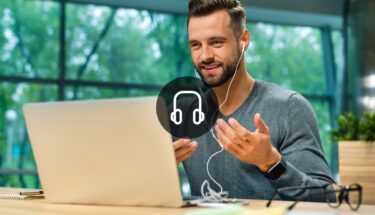 A man with earphones talking into a computer screen