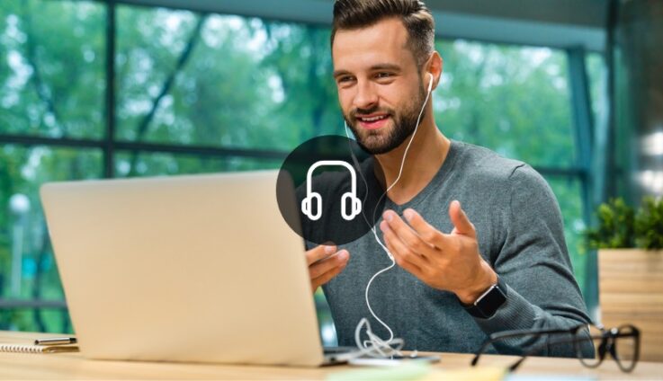 A man with earphones talking into a computer screen