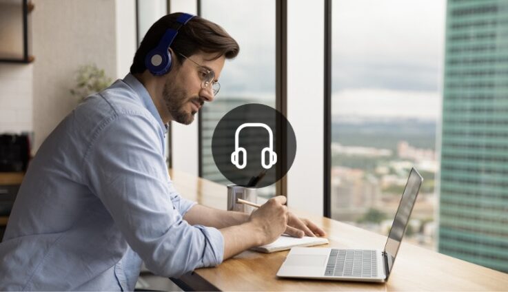 Professionally dressed man looking at computer screen and writing on a notepad