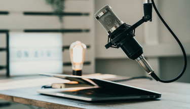 A laptop and podcast microphone on top of a desk