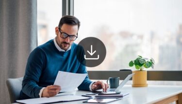 A man with glasses sitting in desk and reviewing a document
