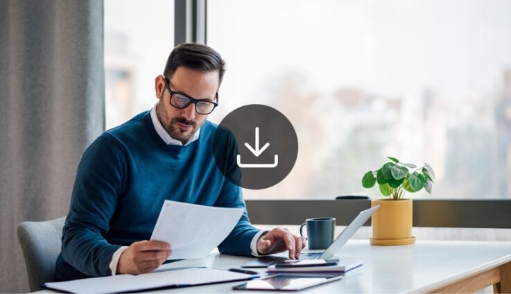 A man with glasses sitting in desk and reviewing a document