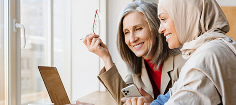 Two women smiling and looking into a computer screen
