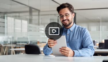 A smiling man with glasses looking at at tablet