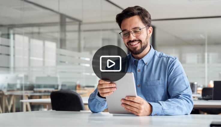 A smiling man with glasses looking at at tablet