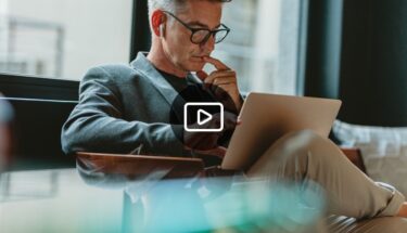 Man with glasses and headphones reviewing something on his computer