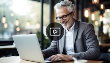 A man with glasses professionally dressed typing on a laptop computer
