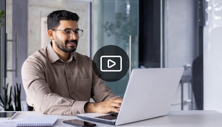 A man dressed in business casual sitting down and typing on laptop computer