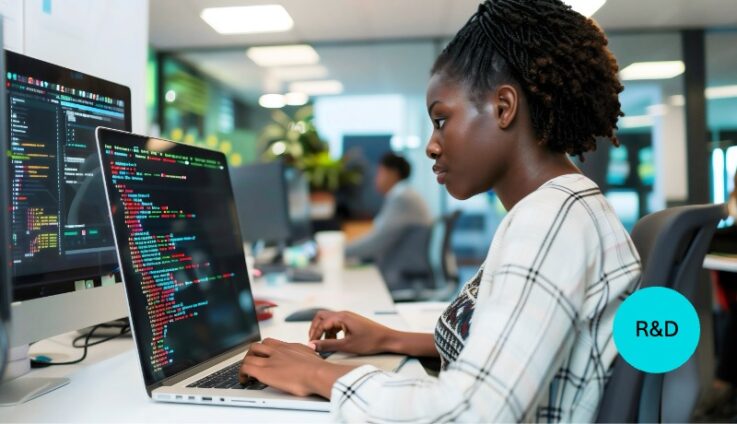 A woman in an office setting coding in her computer