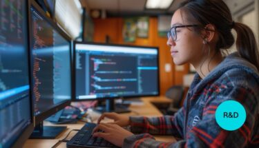 A woman works on coding in her computer in an engineering research and development setting