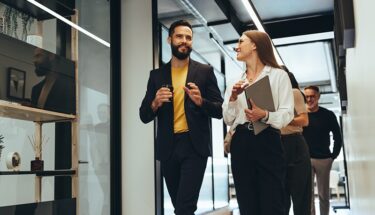 A man and a woman walking in an office setting