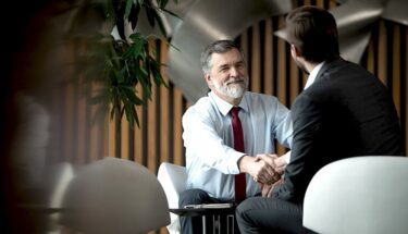 Two professionally dressed men shaking hands in an office setting