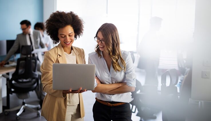 Two women in office looking at laptop