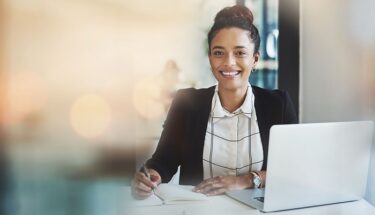 A woman professionally dressed smiling in a desk