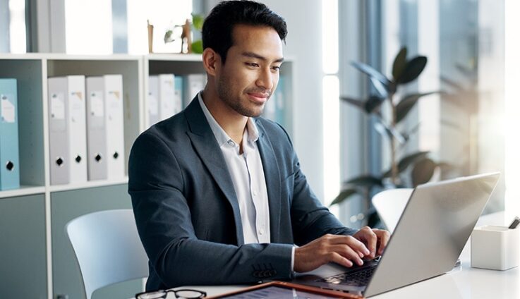 A man sitting in a desk and typing in a computer