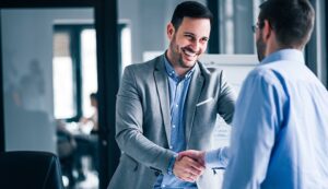 Two men in business attire smiling and shaking hands after completing LP transfers with Ontra.