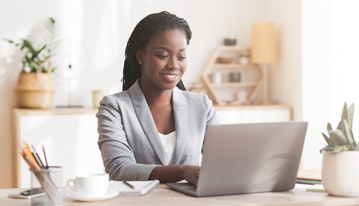 A woman sitting in a desk typing into a laptop