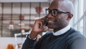 A man with glasses speaking on a cell phone