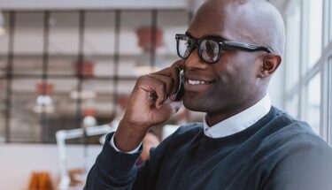 A man with glasses speaking on a cell phone