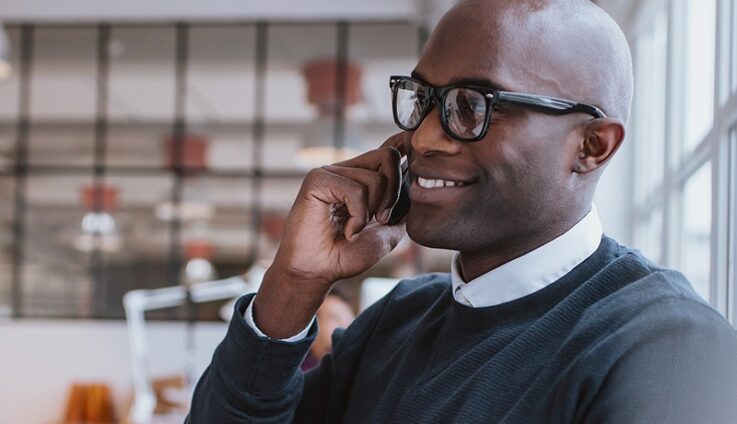A man with glasses speaking on a cell phone