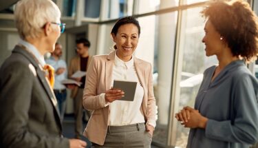 A softly blurred image of people working collaboratively standing next to each other, suggesting teamwork.