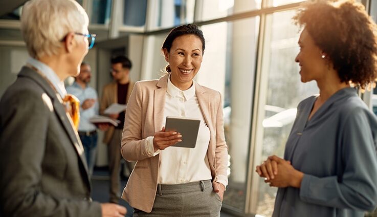 A softly blurred image of people working collaboratively standing next to each other, suggesting teamwork.