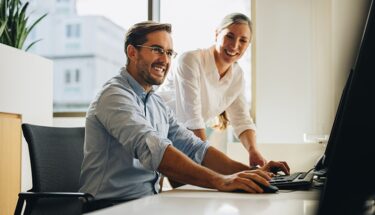Man and woman laughing and looking at computer screen
