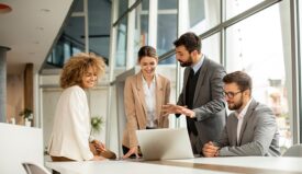 Four business professionals discussing something from a computer screen in an office setting