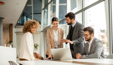 Four business professionals discussing something from a computer screen in an office setting