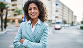 A woman in a suit crossing her hands outside