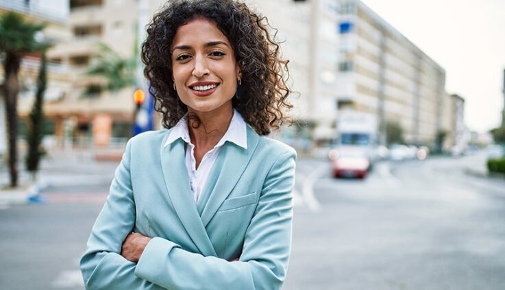 A woman in a suit crossing her hands outside