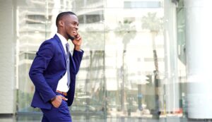 A man in a suit speaking on a cell phone outside