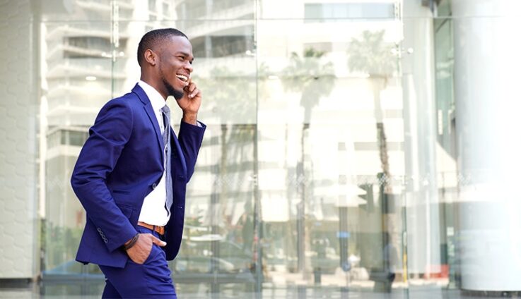 A man in a suit speaking on a cell phone outside