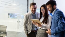 A woman showing two men something on a tablet in an office setting