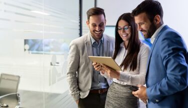 A woman showing two men something on a tablet in an office setting