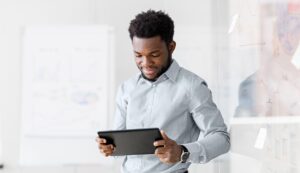 A man wearing a dress shirt looking at a tablet