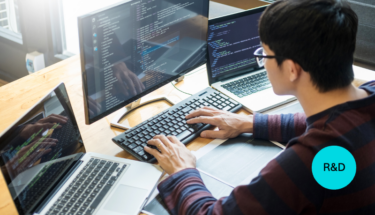 An Asian man with glasses is working at a desktop computer.